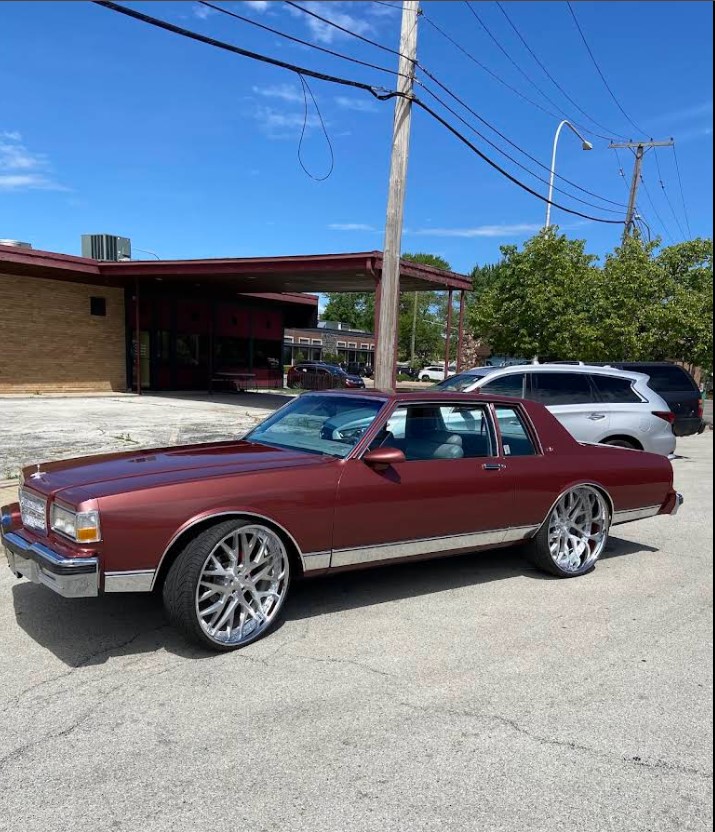 Classic Chevrolet on polished chrome wheels outside the shop