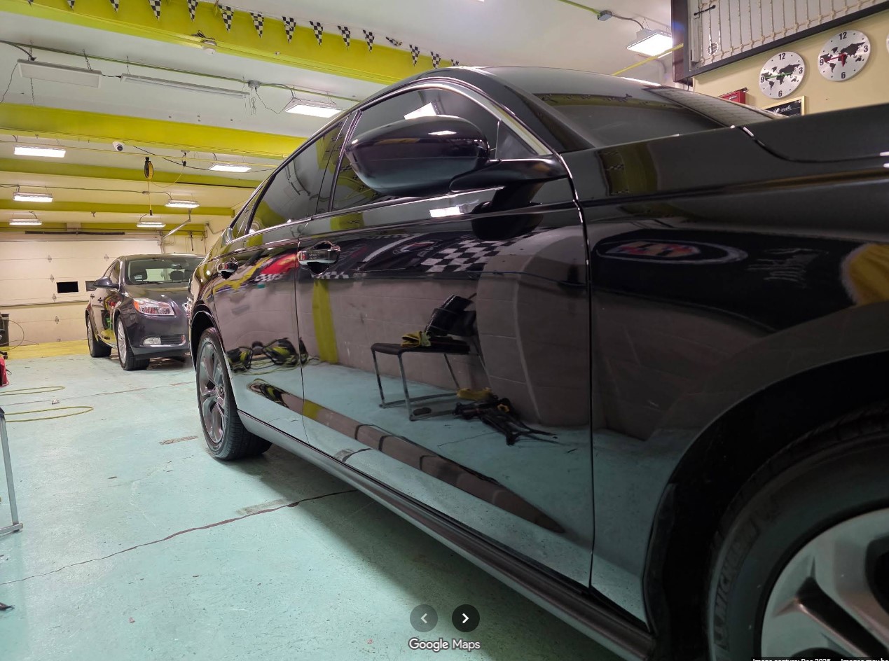Black sedan with a mirror-gloss finish inside the Pro Auto Detail shop